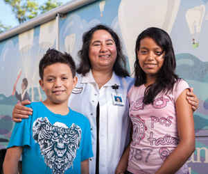 Dentist Mahasti Chalajour with students Domingo and Lucero Venegas in front of the Memorial Hermann Healthcare System Mobile Dental Van.